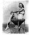 Mona Freeman, black & white leggy pose sitting on rattan chair